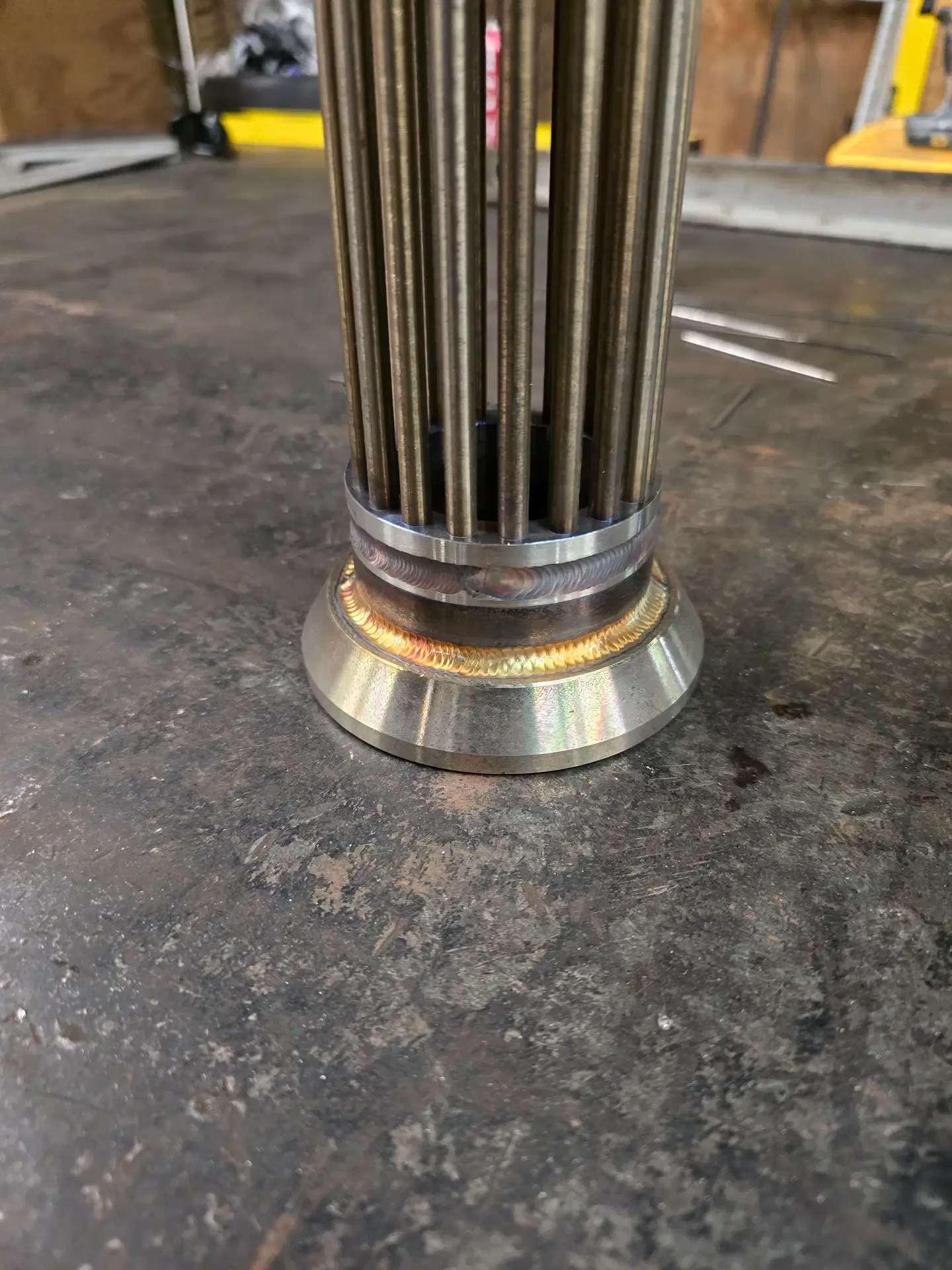 Close-up of a clean stainless-steel TIG weld joining a pipe assembly to a base flange